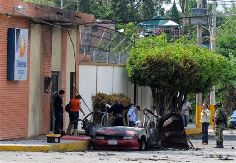 A soldier and investigators work at the site where a vehicle exploded outside the Televisa network in the northern city of Ciudad Victoria, Mexico, on Friday.